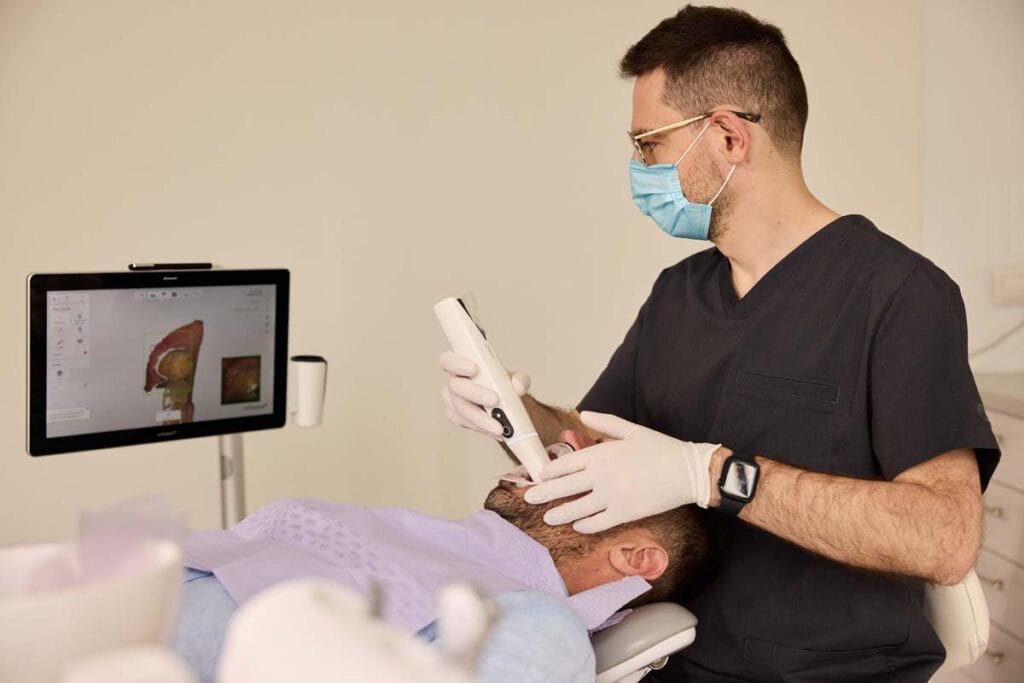 Dentysta wykonujący cyfrowe skanowanie jamy ustnej pacjenta za pomocą skanera wewnątrzustnego 3D.