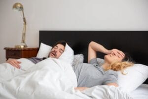sfrustrowana kobieta słuchająca jak jej partner chrapie
