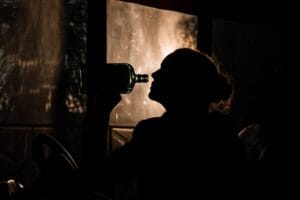 Sylwetka kobiety pijącej alkohol z butelki – problem uzależnienia od alkoholu i potrzeba leczenia nałogu.